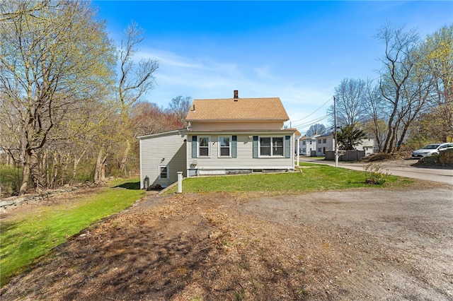 34 Bates Ave, Coventry, RI 02816 - view of front of property featuring a chimney, dirt driveway, a front yard, and a shingled roof