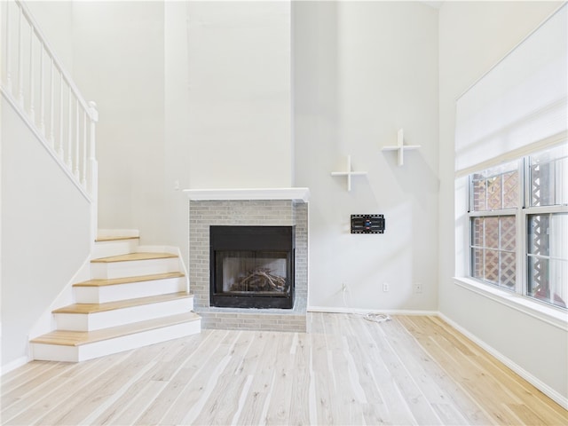 626 Smithfield Rd Unit 909, North Providence, RI 02904 - unfurnished living room with a towering ceiling, wood finished floors, stairway, a fireplace, and baseboards