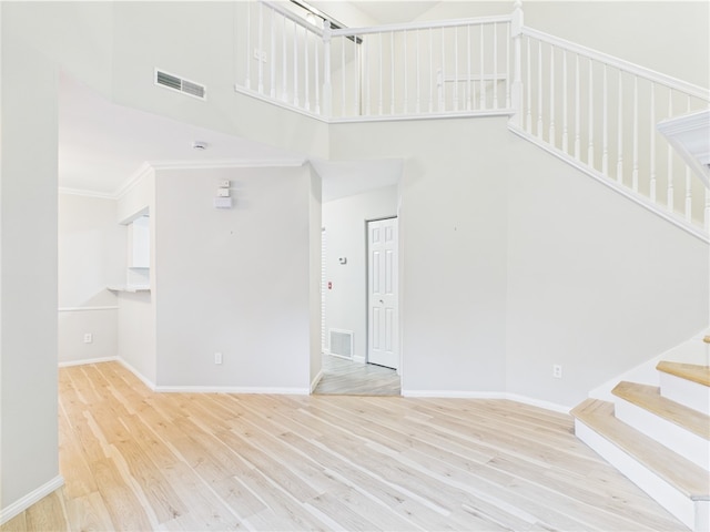 626 Smithfield Rd Unit 909, North Providence, RI 02904 - unfurnished living room featuring stairs, a towering ceiling, wood finished floors, baseboards, and crown molding