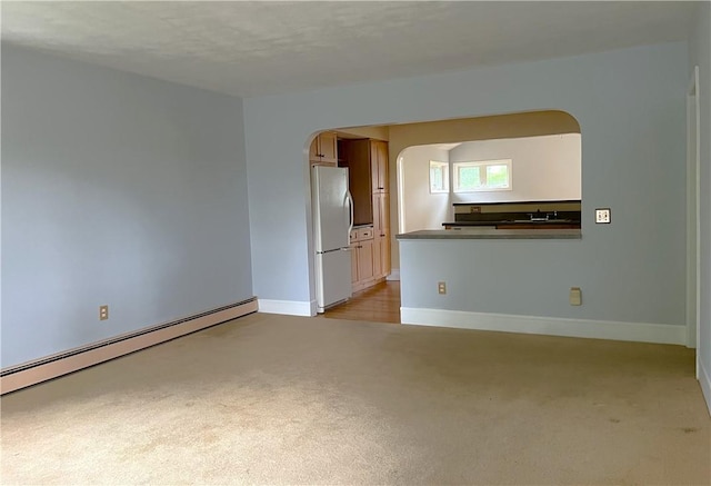 10 Cavalier Rd, Narragansett, RI 02882 - empty room with arched walkways, baseboard heating, light colored carpet, baseboards, and a sink