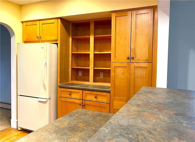 10 Cavalier Rd, Narragansett, RI 02882 - kitchen with freestanding refrigerator, a baseboard radiator, arched walkways, wood finished floors, and brown cabinetry