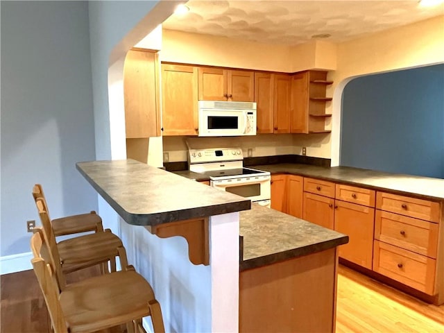 10 Cavalier Rd, Narragansett, RI 02882 - kitchen featuring white appliances, a peninsula, open shelves, a kitchen bar, and dark countertops