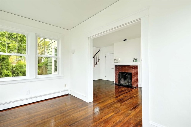77 Glen Ave, Cranston, RI 02905 - unfurnished living room with a baseboard heating unit, wood finished floors, baseboards, stairway, and a brick fireplace
