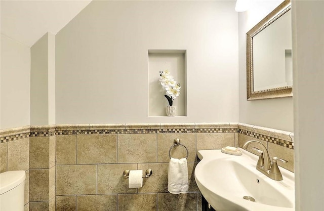 77 Glen Ave, Cranston, RI 02905 - half bathroom featuring a sink, tile walls, wainscoting, toilet, and vaulted ceiling
