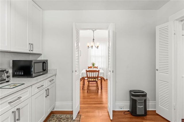 12 Arlington St, Westerly, RI 02891 - kitchen with black microwave, a chandelier, light wood-style flooring, and light countertops