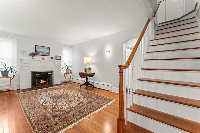 12 Arlington St, Westerly, RI 02891 - living room featuring a brick fireplace, stairway, hardwood / wood-style floors, and a baseboard heating unit