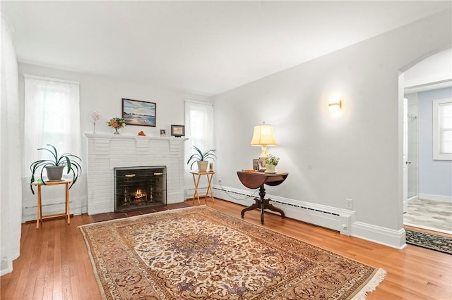 12 Arlington St, Westerly, RI 02891 - living area with a fireplace, wood finished floors, baseboard heating, baseboards, and arched walkways