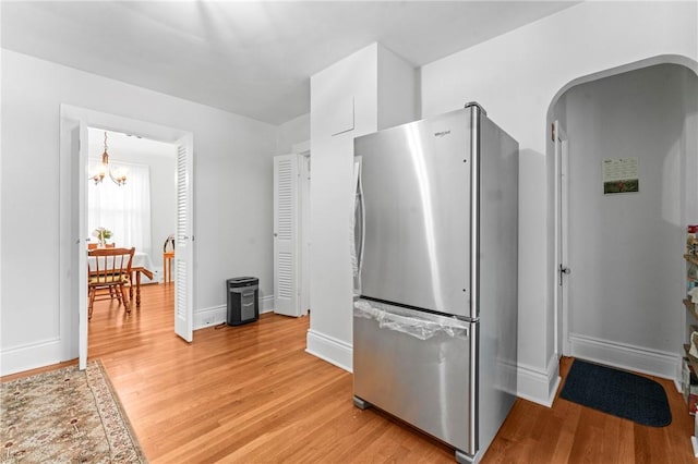 12 Arlington St, Westerly, RI 02891 - kitchen with freestanding refrigerator, a chandelier, light wood finished floors, and baseboards