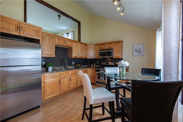 417 Privilege St, Woonsocket, RI 02895 - kitchen with stainless steel appliances, vaulted ceiling, tasteful backsplash, a sink, and light wood-style flooring