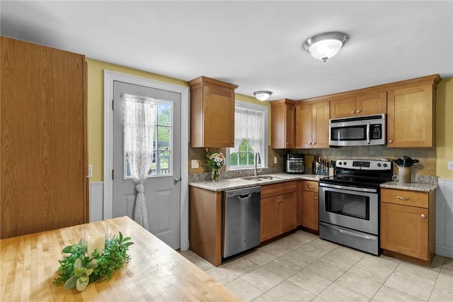 223 Chopmist Hill Rd, Glocester, RI 02814 - kitchen featuring appliances with stainless steel finishes, a sink, decorative backsplash, brown cabinetry, and light stone countertops