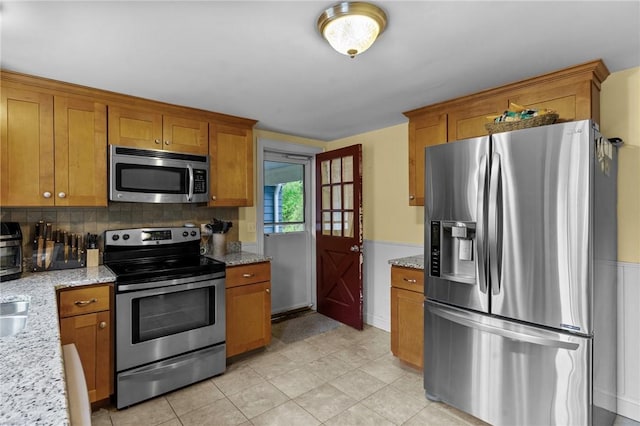 223 Chopmist Hill Rd, Glocester, RI 02814 - kitchen featuring appliances with stainless steel finishes, brown cabinets, tasteful backsplash, and light stone countertops