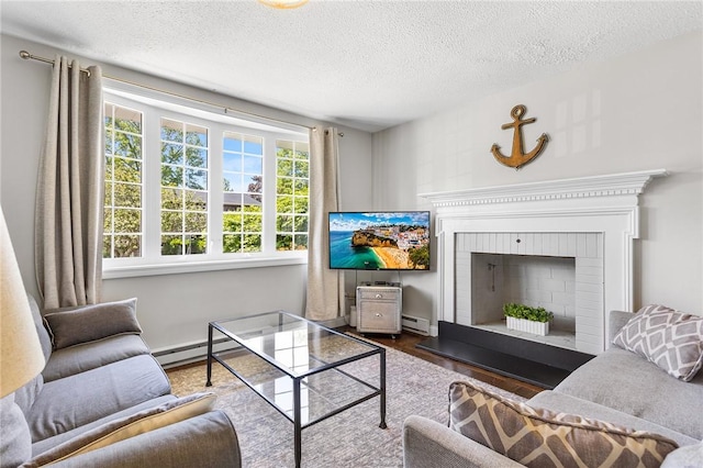 25 Old Pine Rd, Narragansett, RI 02882 - living room with a baseboard heating unit, wood finished floors, a textured ceiling, and a brick fireplace