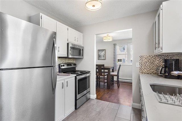 25 Old Pine Rd, Narragansett, RI 02882 - kitchen featuring stainless steel appliances, a sink, backsplash, white cabinetry, and light stone counters