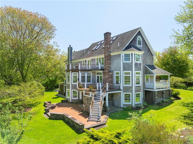 38 Westwind Dr, Jamestown, RI 02835 - back of house with a balcony, a lawn, a patio area, a chimney, and a wooden deck