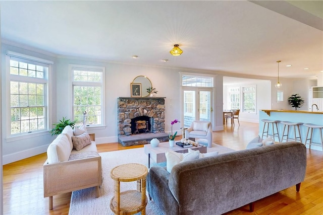 38 Westwind Dr, Jamestown, RI 02835 - living area featuring baseboards, ornamental molding, a stone fireplace, and light wood-style flooring