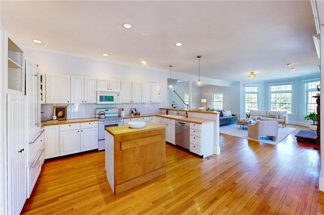 38 Westwind Dr, Jamestown, RI 02835 - kitchen with white appliances, butcher block countertops, a sink, open floor plan, and a peninsula