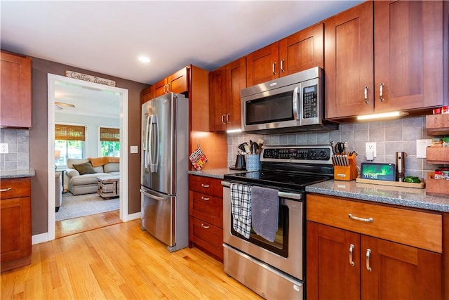 45 Nichols Rd, North Kingstown, RI 02852 - kitchen with stainless steel appliances, light wood finished floors, brown cabinetry, stone counters, and backsplash