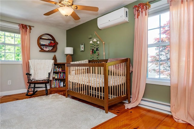 45 Nichols Rd, North Kingstown, RI 02852 - bedroom featuring a wall mounted air conditioner, a baseboard radiator, wood finished floors, baseboards, and a nursery area