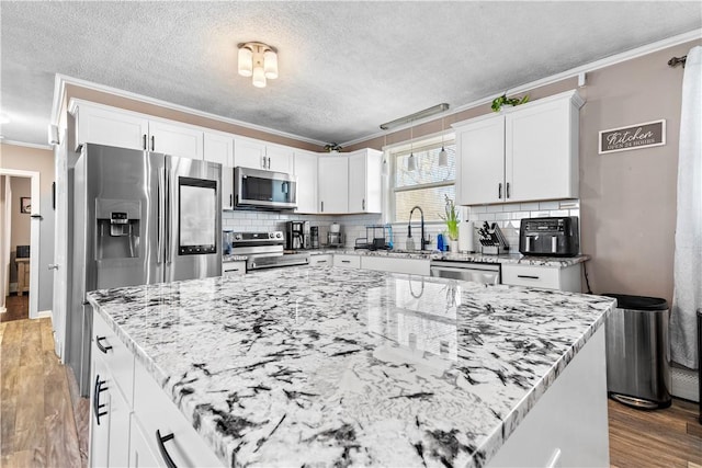 37 Boundary Ave, Providence, RI 02909 - kitchen featuring stainless steel appliances, crown molding, wood finished floors, white cabinetry, and decorative backsplash