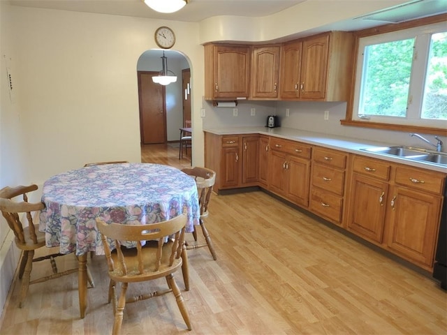13 Ivy Pl, Lincoln, RI 02865 - kitchen featuring a sink, brown cabinetry, arched walkways, light wood-style flooring, and light countertops