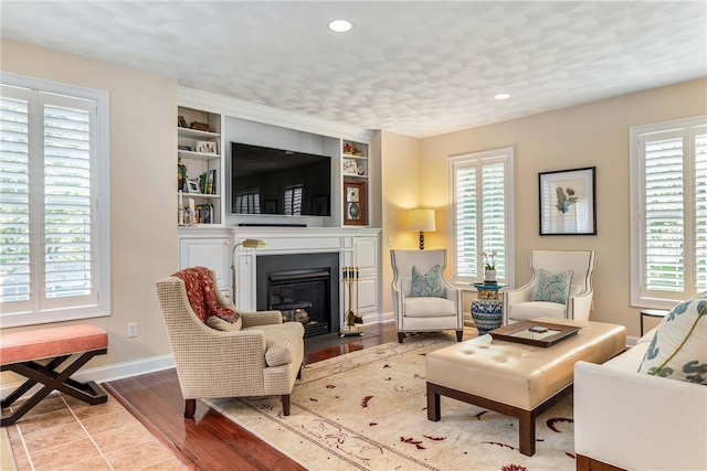 83 Preservation Way S, Kingstown, RI 02879 - living area featuring a fireplace with flush hearth, recessed lighting, baseboards, built in shelves, and wood finished floors