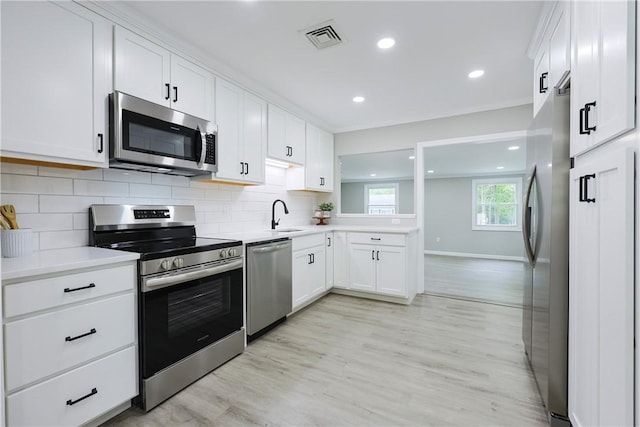 31 Forbes St, East Providence, RI 02915 - kitchen with appliances with stainless steel finishes, light wood finished floors, backsplash, light countertops, and white cabinetry