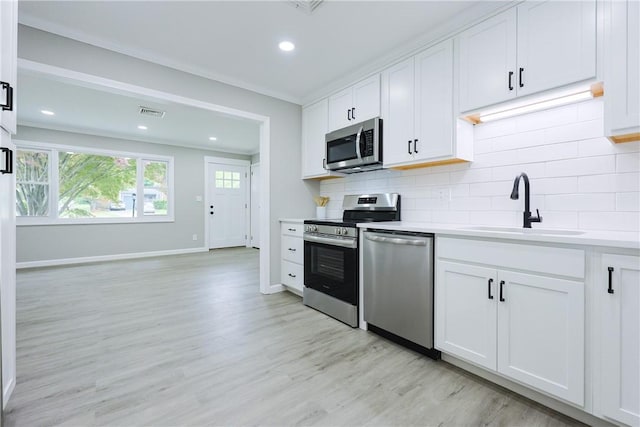 31 Forbes St, East Providence, RI 02915 - kitchen with stainless steel appliances, a sink, light wood-type flooring, backsplash, and light countertops