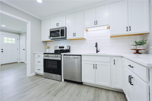 31 Forbes St, East Providence, RI 02915 - kitchen with appliances with stainless steel finishes, crown molding, light wood finished floors, a sink, and decorative backsplash