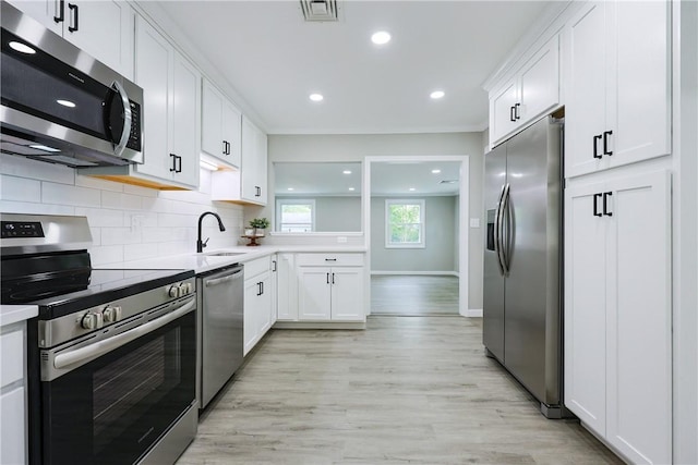 31 Forbes St, East Providence, RI 02915 - kitchen with appliances with stainless steel finishes, light wood-type flooring, backsplash, white cabinets, and recessed lighting