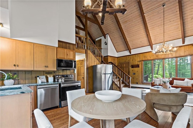 310 Old Coach Rd, Charlestown, RI 02813 - dining space featuring a chandelier, wooden walls, light wood-style flooring, stairway, and high vaulted ceiling