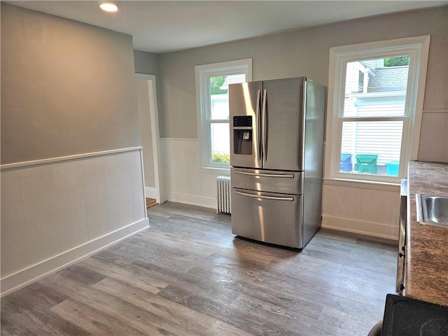 29 Arthur St, Warwick, RI 02888 - kitchen with stainless steel fridge, wood finished floors, radiator, a sink, and wainscoting