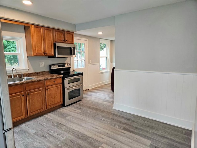 29 Arthur St, Warwick, RI 02888 - kitchen with appliances with stainless steel finishes, a sink, light wood-style floors, brown cabinetry, and dark countertops