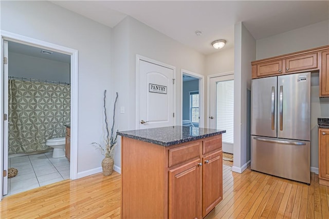 10 Kristin Ct, Coventry, RI 02816 - kitchen with freestanding refrigerator, light wood-style floors, dark stone countertops, and brown cabinets