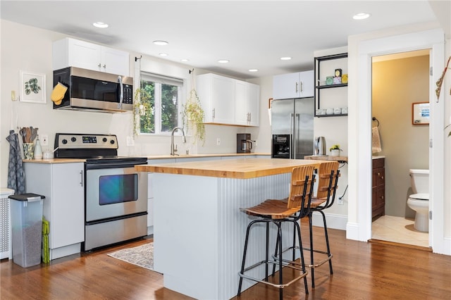 405 Eaton St, Providence, RI 02908 - kitchen featuring stainless steel appliances, butcher block counters, a kitchen bar, white cabinets, and recessed lighting