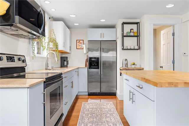 405 Eaton St, Providence, RI 02908 - kitchen featuring stainless steel appliances, a sink, light wood-style flooring, white cabinetry, and recessed lighting