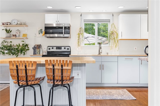 405 Eaton St, Providence, RI 02908 - kitchen featuring stainless steel appliances, white cabinets, light wood finished floors, a sink, and recessed lighting