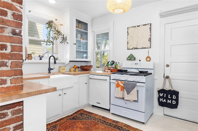 143 Ivy St, Providence, RI 02906 - kitchen featuring white appliances, a sink, a wall mounted air conditioner, white cabinets, and light countertops