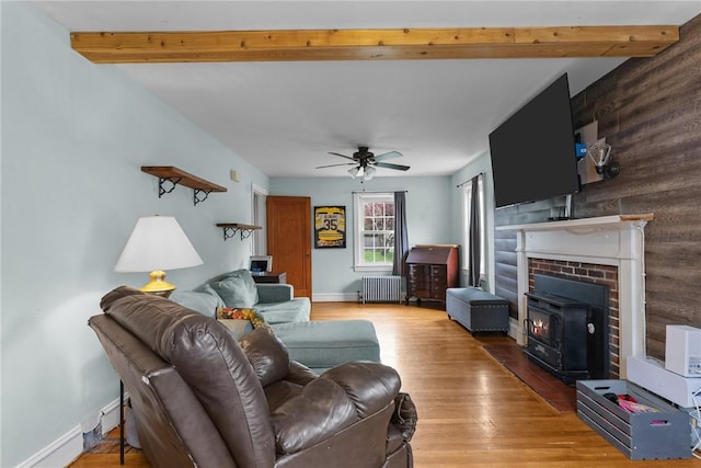 95 George Arden Ave, Warwick, RI 02886 - living room with radiator heating unit, a wood stove, light wood-style flooring, beam ceiling, and a ceiling fan