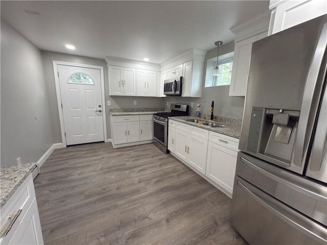 103 Pleasent St, Woonsocket, RI 02895 - kitchen with appliances with stainless steel finishes, a sink, white cabinets, light stone counters, and wood finished floors