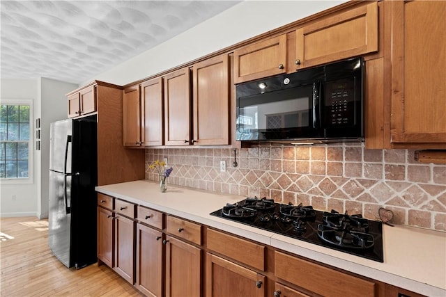 32 Trolley Ln, Westerly, RI 02891 - kitchen with black appliances, brown cabinets, light countertops, tasteful backsplash, and light wood-style flooring