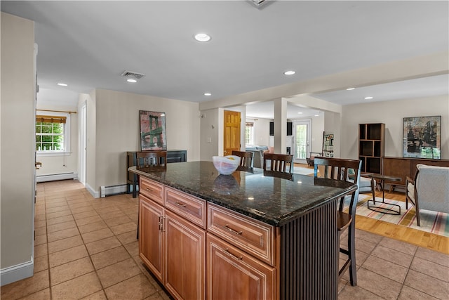 30 First School St, Bristol, RI 02809 - kitchen with a breakfast bar, light tile patterned floors, a baseboard radiator, a kitchen island, and baseboard heating
