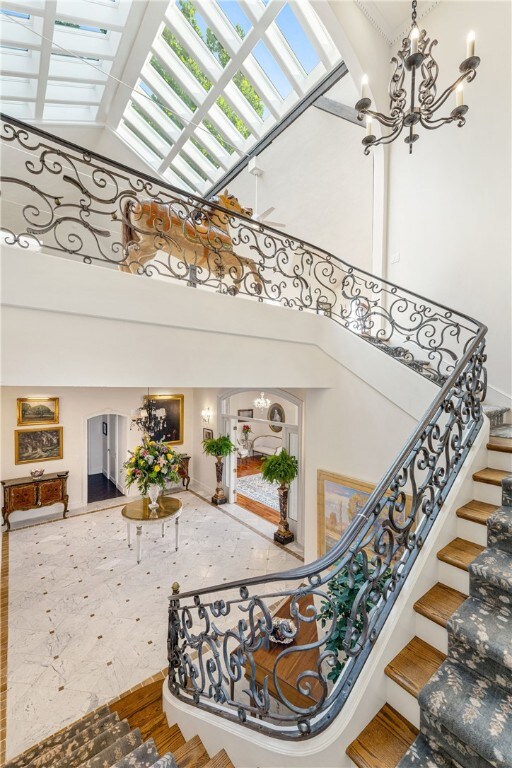 63 Coggeshall Ave, Newport, RI 02840 - staircase with a chandelier, a towering ceiling, and a skylight
