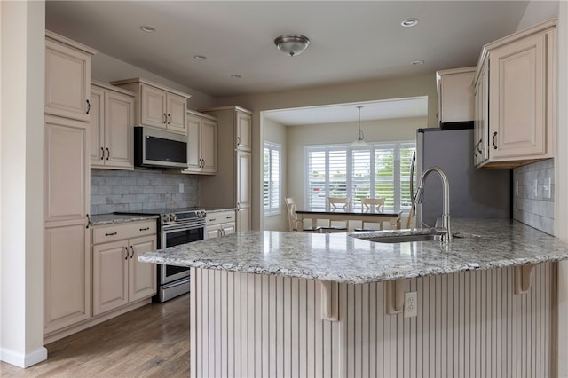 109 Chickadee Ln Unit A24, South Kingstown, RI 02879 - kitchen with stainless steel appliances, a sink, a peninsula, a breakfast bar, and light wood-style flooring