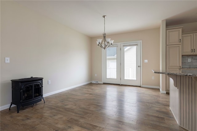 109 Chickadee Ln Unit A24, South Kingstown, RI 02879 - unfurnished dining area featuring a wood stove, a chandelier, dark wood finished floors, and baseboards