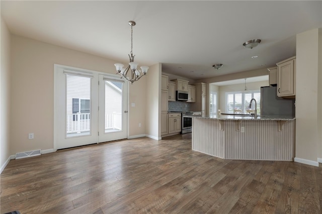 109 Chickadee Ln Unit A24, South Kingstown, RI 02879 - kitchen with stainless steel appliances, a chandelier, a peninsula, wood finished floors, and decorative light fixtures