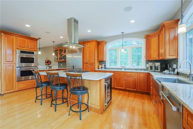 51 Reservoir Rd, Cumberland, RI 02864 - kitchen featuring stainless steel appliances, island exhaust hood, light wood finished floors, brown cabinets, and backsplash