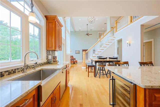 51 Reservoir Rd, Cumberland, RI 02864 - kitchen with wine cooler, brown cabinets, light wood finished floors, tasteful backsplash, and a sink