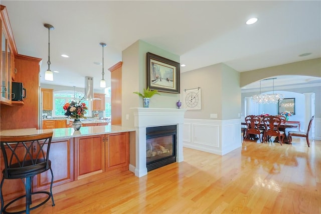 51 Reservoir Rd, Cumberland, RI 02864 - bar with light wood-type flooring, arched walkways, hanging light fixtures, a glass covered fireplace, and wainscoting