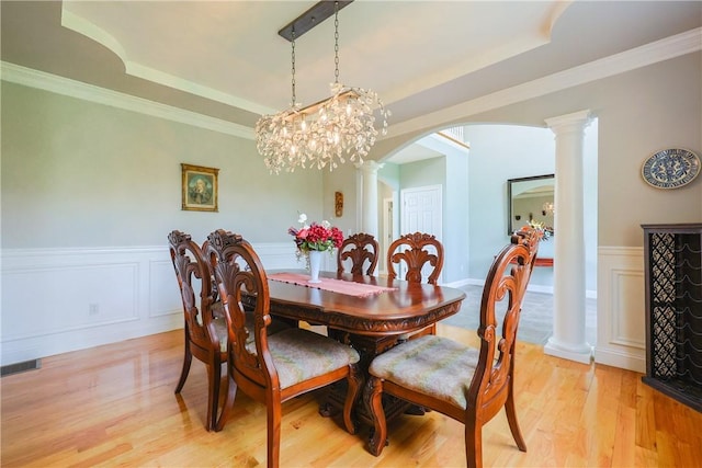 51 Reservoir Rd, Cumberland, RI 02864 - dining space featuring arched walkways, a raised ceiling, wainscoting, decorative columns, and light wood-style flooring