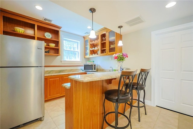 51 Reservoir Rd, Cumberland, RI 02864 - kitchen with stainless steel appliances, open shelves, brown cabinets, a breakfast bar area, and light tile patterned floors